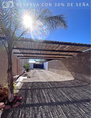 a wooden pergola over a road with a palm tree at Cabaña Alpina del Centro in Chilecito