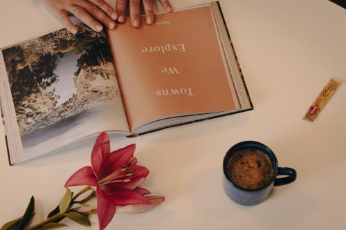 a person reading a book on a table with a cup of coffee at Strahan Beach Tourist Park in Strahan