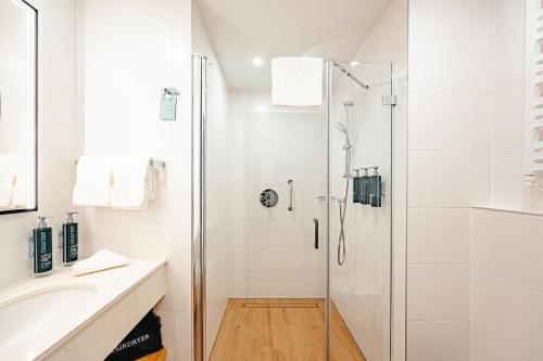 a white bathroom with a shower and a sink at Hilton Garden Inn Radom in Radom