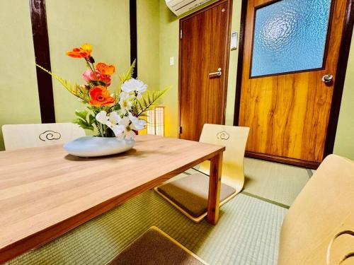 a wooden table with a vase of flowers on it at 和居 霊羽 日本の伝統を感じる趣ある邸宅 in Osaka