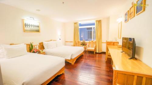 a hotel room with two beds and a television at Romance Hotel in Hue