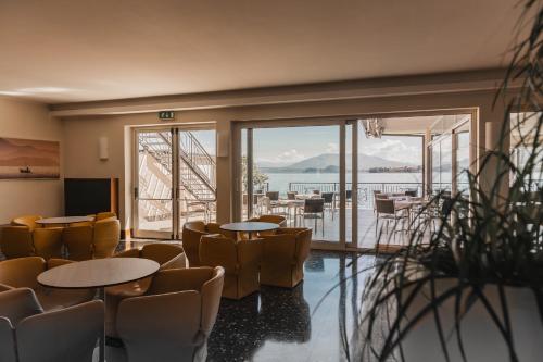 a room with chairs and tables and a view of the water at Hotel Bel Sit in Meina