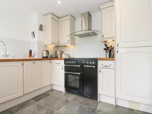 a kitchen with white cabinets and a black oven at Godrevy in Penzance