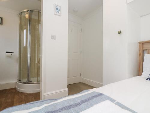 a white bedroom with a shower and a bed at Godrevy in Penzance