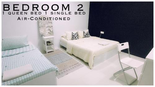 a white bedroom with a bed and a chair at Harris Homestay Gerik Town, Free Wifi & Netflix in Gerik