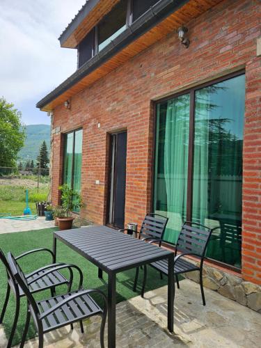 a picnic table and two chairs on a patio at WoodStar/ტყის ვარსკვლავი in Ambrolauri