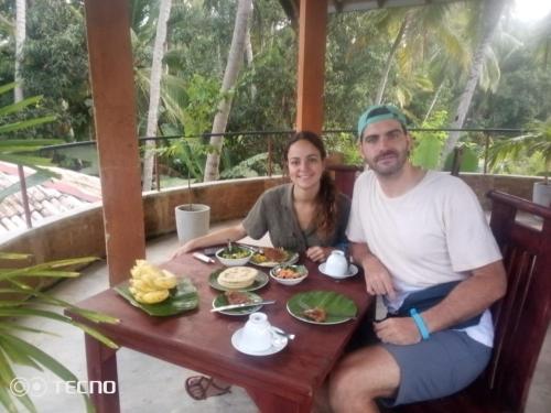 a man and woman sitting at a table with food at Rice Rice Villas in Tissamaharama