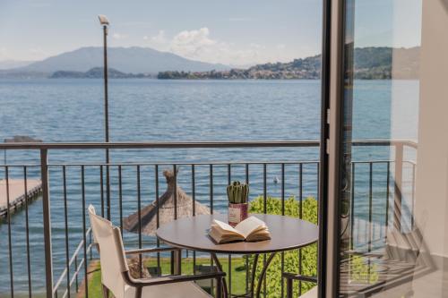 a table with a book on a balcony with a view of the water at Hotel Bel Sit in Meina