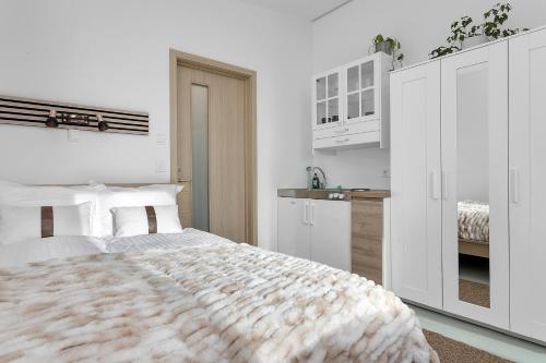 a white bedroom with a bed and a kitchen at Klettar - The Old Hatchery Iceland in Fludir