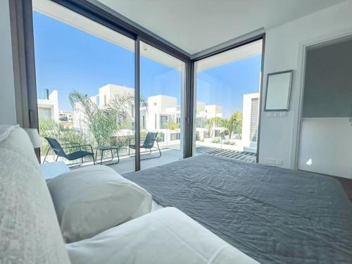 ein Schlafzimmer mit einem Bett und einem großen Fenster in der Unterkunft Azure Breeze Villa - Roof Garden & Sea Views in Protaras