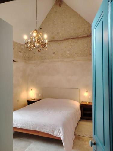- une chambre avec un lit blanc et un lustre dans l'établissement Closerie de Montaimé, à Amboise