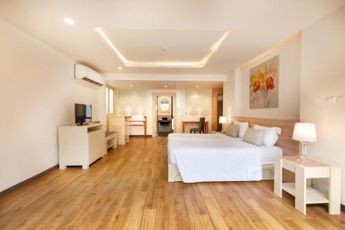 a bedroom with a white bed and a living room at The Briza Beach Resort, Samui - SHA Plus in Chaweng