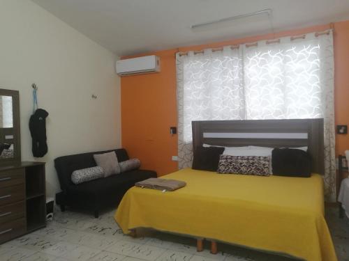 a bedroom with a yellow bed and a couch at Naj Wayak´ Departamentos in Valladolid