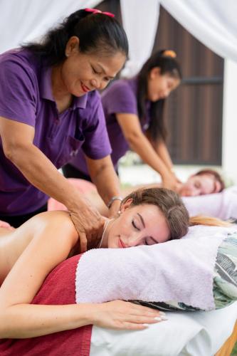 a woman laying on a bed with a masseur at The Briza Beach Resort, Samui - SHA Plus in Chaweng