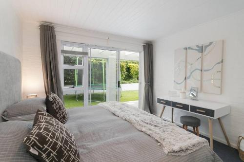 a bedroom with a bed and a desk and a window at Herons House in Knysna