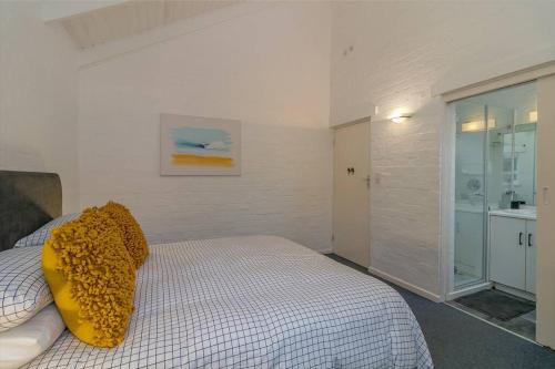 a bedroom with a bed with a yellow pillow on it at Herons House in Knysna