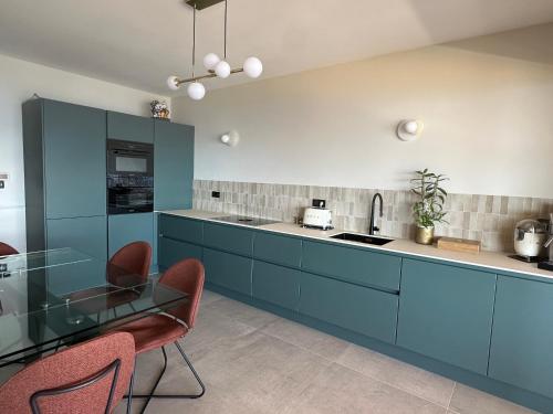 une cuisine avec des armoires bleues et une table en verre dans l'établissement Appartement de standing, vue mer, 3 chambres, à Ajaccio