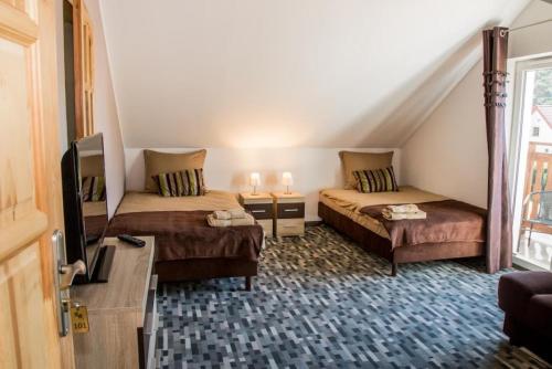 a small room with two beds and a tv at Ośrodek nad jeziorem - Radew Rosnowo in Rosnowo