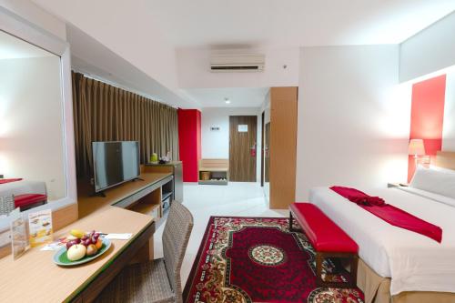 a hotel room with a bed and a desk and a tv at Atrium Premiere Hotel Yogyakarta Ambarukmo in Yogyakarta