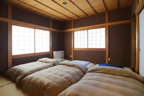 a room with four large beds in it with windows at ぽつぽつあん in Ise