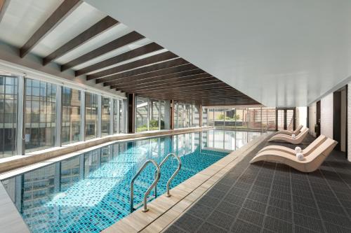 a large swimming pool in a building with windows at Fraser Place Wujiaochang Shanghai - Adjoin business center, free minibar in Shanghai