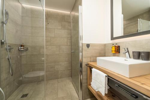 a bathroom with a glass shower and a sink at AvenidA Panorama Suites in Kaprun