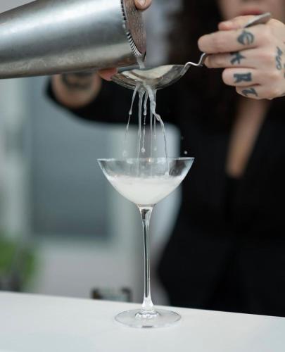 a person pouring a drink into a martini glass at Cristallo Park Hotel in Portovenere