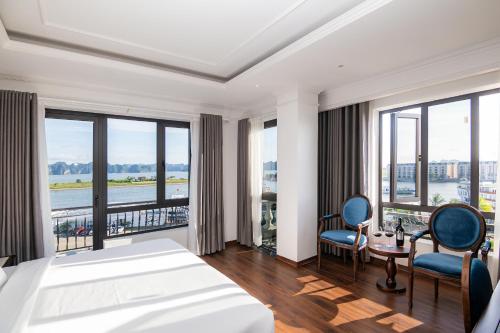 a bedroom with a bed and chairs and windows at Charmhill Hotel - Tuần Châu in Ha Long