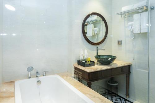 a bathroom with a tub and a sink and a mirror at Charmhill Hotel - Tuần Châu in Ha Long