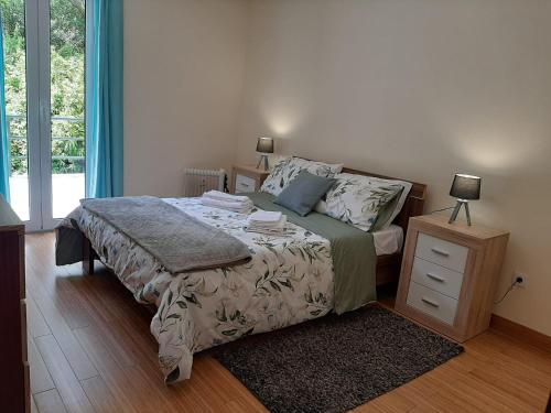 a bedroom with a bed with a night stand and a window at Residência do Saramago in São Vicente
