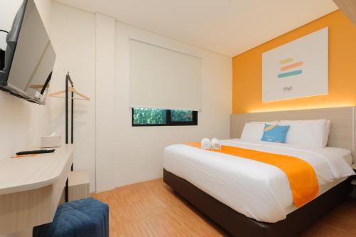 a bedroom with a bed and a desk and a tv at Sans Hotel Tajur Bogor in Bantarkamang