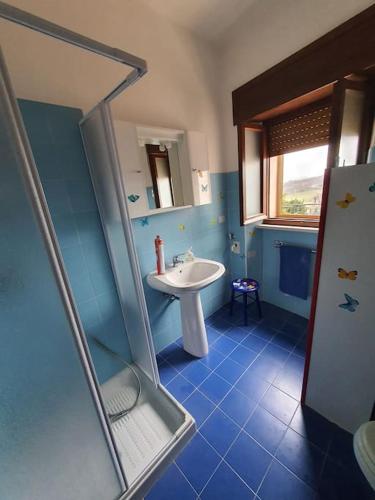 a blue bathroom with a sink and a shower at La quiete tra le montagne in Apiro