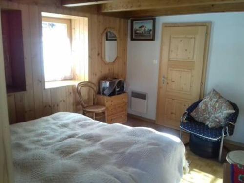 a bedroom with a bed and a chair and a window at Chalet 3 pièces de caractère in Mayoux
