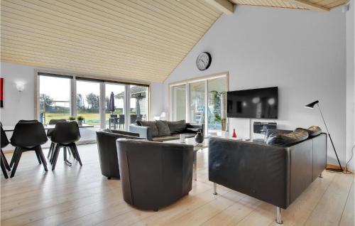 a living room with leather furniture and a clock on the wall at Lovely Home In Løkken With Wifi in Løkken