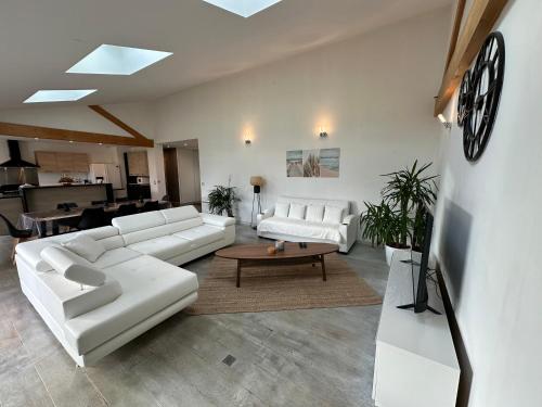 d'un salon doté d'un mobilier blanc et d'une horloge murale. dans l'établissement La Roselière - CDDT, à Yves