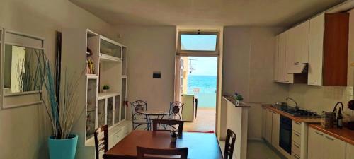 a kitchen and dining room with a table and a view of the ocean at On The Beach SORRENTO in Massa Lubrense
