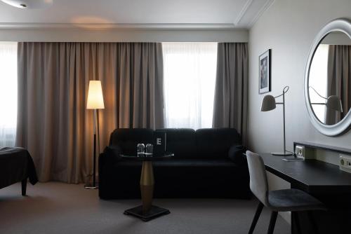 a living room with a couch and a table and a mirror at Elite Stadshotellet Luleå in Luleå