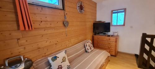 Cette chambre est dotée d'un mur en bois avec un banc et une télévision. dans l'établissement EQUINOXE-203- Appt 4 pers Souplex, à Les Deux Alpes
