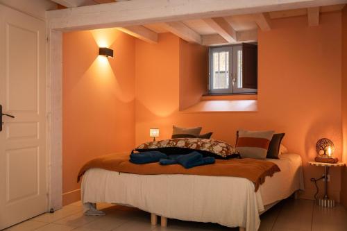 une chambre avec un lit avec un mur orange dans l'établissement Le jardin de la Paix - Centre historique, à Sarlat-la-Canéda