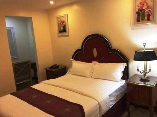 a bedroom with a large bed with white sheets at Rainbowland Hotel in Olongapo