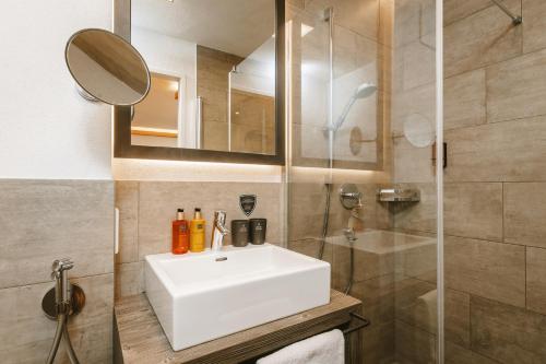 a bathroom with a white sink and a shower at AvenidA Panorama Suites in Kaprun