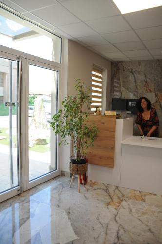 a woman sitting at a counter in a room with a plant at Sobe Sova Kikinda in Kikinda