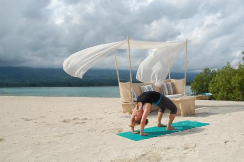 a child doing a yoga pose on the beach at Badian Island Wellness Resort in Badian