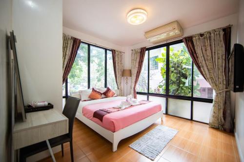 Un dormitorio con una cama, un escritorio y ventanas. en ชญาดา การ์เด้นเฮาส์ & รีสอร์ท Hotel, en Nakhon Ratchasima