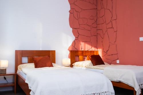 two beds in a room with a red wall at Penzion Sankt Johann in Liptovský Ján