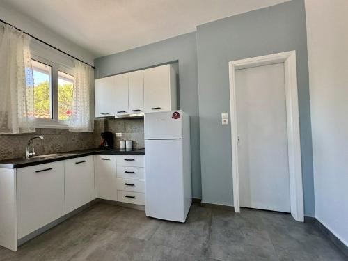 una cucina con mobili bianchi e un frigorifero bianco di Alexander apartment 3 a Spartià