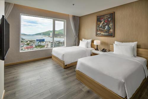 a hotel room with two beds and a large window at Abogo Apartment FHome Riverside in Da Nang