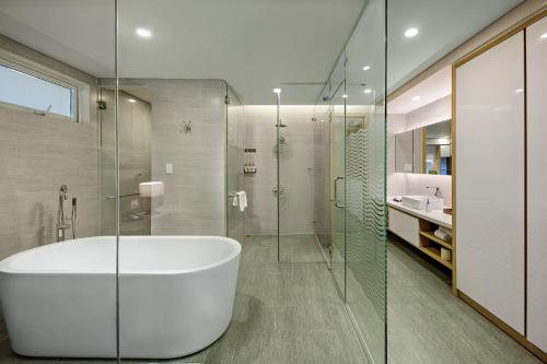 a bathroom with a tub and a glass shower at Abogo Apartment FHome Riverside in Da Nang