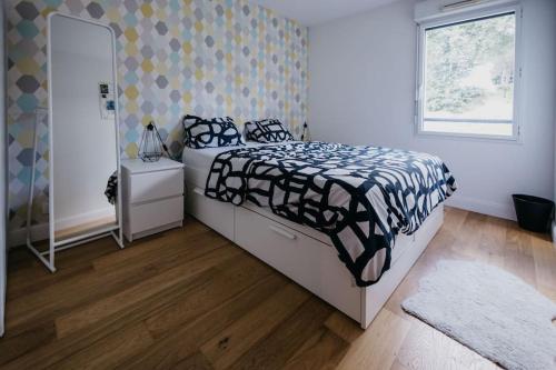 une chambre avec un lit avec une couette noire et blanche dans l'établissement Appartement cosy avec wifi à 15 min de Rennes, à Crévin