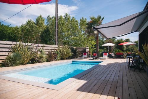 - une piscine avec une terrasse et un parasol dans l'établissement Villa Bet Loc 14 personnes, à Saubrigues